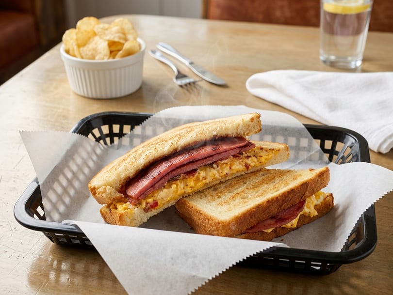 Grilled cheese sandwich with bacon served in a black basket.